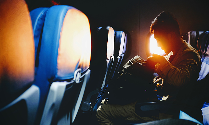 a man looking through his bag on an airplane