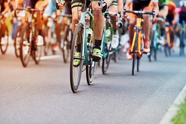 close up image of lots of cyclists legs and their colourful bikes during a cycling race